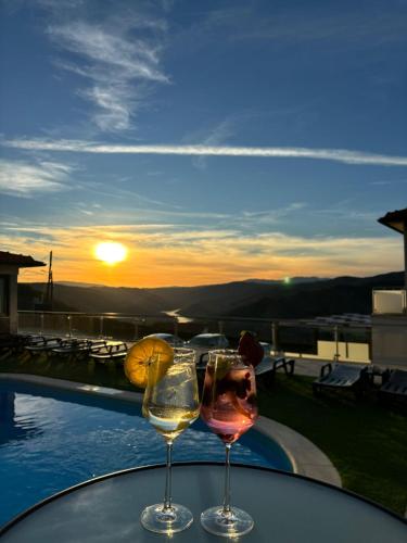 two glasses of wine sitting on a table with the sunset at Socalcos do Douro House in Valença do Douro