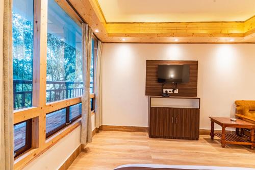 a living room with a large window and a tv at The Golden Retreat Hotel in Pelling in Pelling