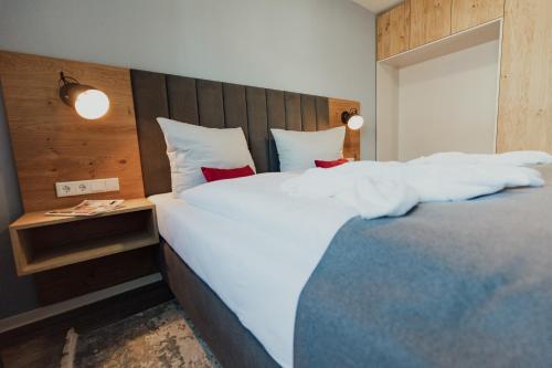 a bedroom with a large bed with white sheets and red pillows at Fewo Graureiher Obergeschoss in Hooksiel