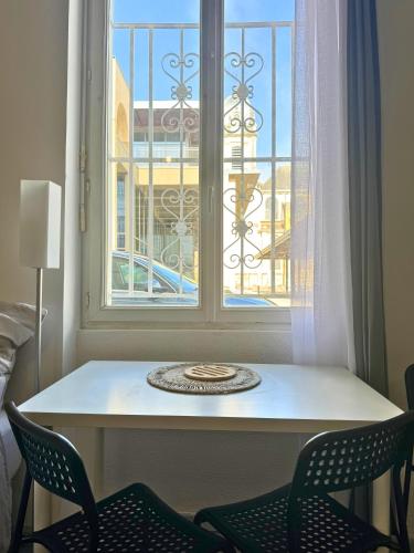 une table et deux chaises devant une fenêtre dans l'établissement Mini Nid - Centre - Wifi - Equipé - Cosy, à Dax