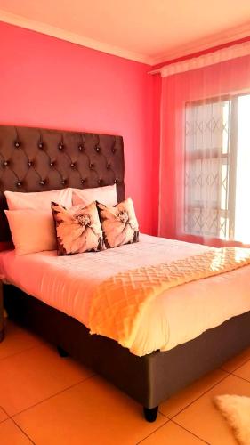 a bedroom with a large bed with pink walls at Palma Spaces Standard in Pretoria