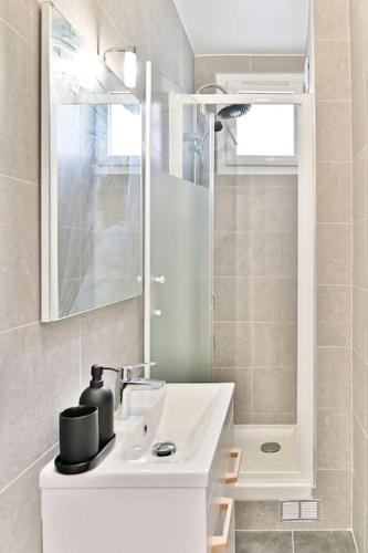 une salle de bain blanche avec un lavabo et une douche dans l'établissement Appartement à Montreuil cosy et confortable - II, à Montreuil