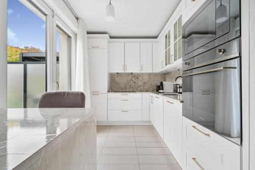 une cuisine avec des placards blancs et une grande fenêtre dans l'établissement L'Evasion - 3 bdr - Jardin - Gym - Disney, à Lognes