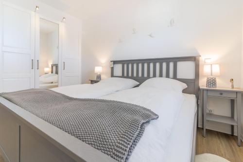 a white bedroom with two beds and a mirror at Fewo Hygge Penthouse in Hooksiel