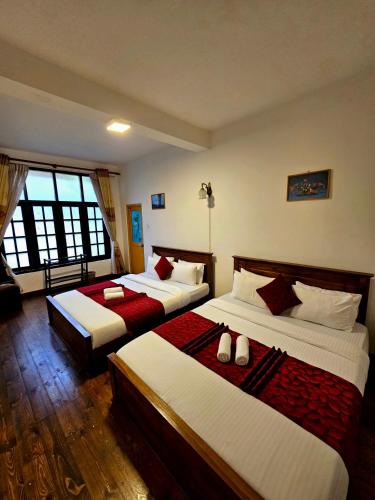 a bedroom with two beds with red and white sheets at Chez Allen in Nuwara Eliya