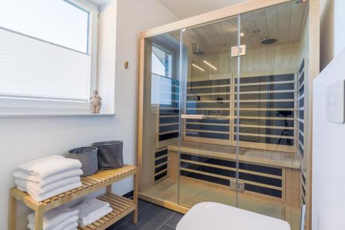 a glass shower in a bathroom with towels at Fewo Hygge Penthouse in Hooksiel