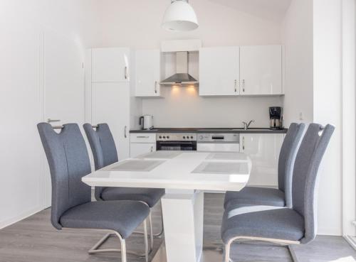a white kitchen with a white table and chairs at Fewo Ausguck Penthouse in Hooksiel