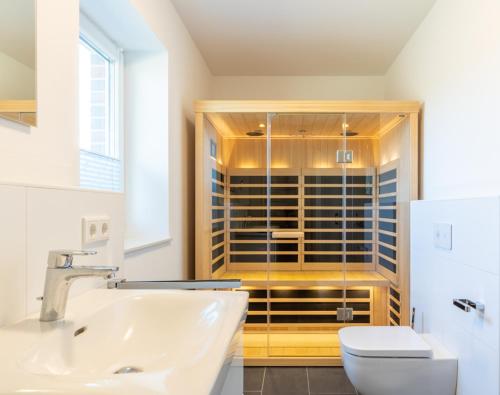 a bathroom with a toilet and a sink and a shower at Fewo Ausguck Penthouse in Hooksiel