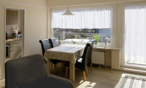 mesa de comedor con sillas y cocina con ventana en Ferienwohnung Klabautermann, en Hooksiel