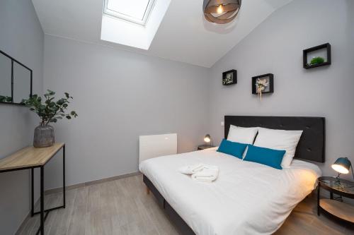 une chambre avec un grand lit blanc avec des oreillers bleus dans l'établissement Gîte Chelona d'Hermann par Chelona'Loc, à Braud-et-Saint-Louis