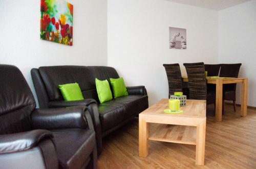 sala de estar con mesa y muebles de cuero negro en Ferienhaus Paula, en Hooksiel