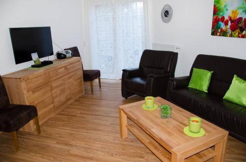 Una sala de estar con un sofá y sillas y un televisor. en Ferienhaus Paula, en Hooksiel