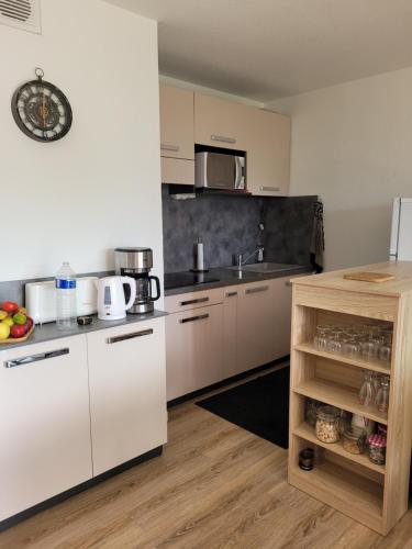 une cuisine avec des armoires blanches et un comptoir dans l'établissement Appartement face au golf en rez de jardin, au Cap d'Agde
