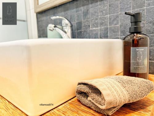 a bathroom sink with a bottle of soap and a towel at Villa Moai 974 in Saint-Leu
