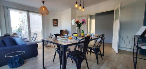 - un salon avec une table, des chaises et un canapé bleu dans l'établissement Le Clemenceau appart-Calais Nord-balcon-plage, à Calais