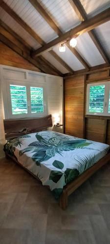 a bedroom with a bed in a room with windows at Ti' Nid Mango Cabane charmante et confortable in Pointe-Noire