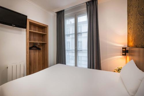 a bedroom with a large white bed with a window at Hotel Daval in Paris
