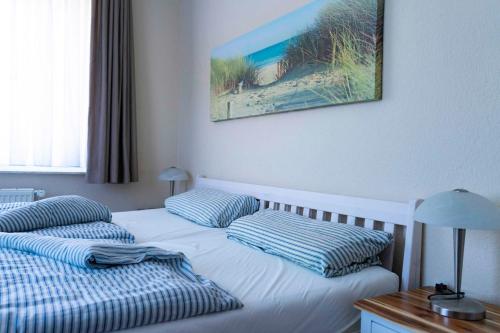 a bed with two pillows and a picture on the wall at Ferienwohnung Krabbe in Hooksiel