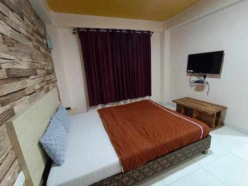 a bedroom with a bed and a flat screen tv at Cental Homestay in Shillong