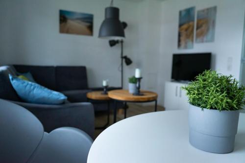 a living room with a couch and a table with a plant at Ferienwohnung Wassmann Hooksiel in Hooksiel