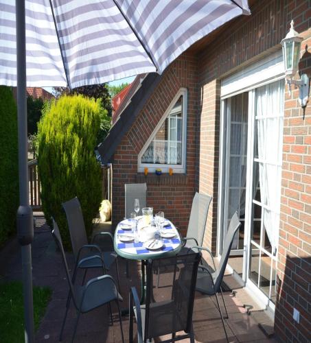 a table with chairs and an umbrella on a patio at Ferienhaus Galle in Hooksiel