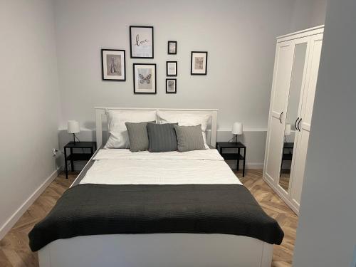 a bedroom with a large white bed with three pictures on the wall at Apartament Frezja in Gryfów Śląski