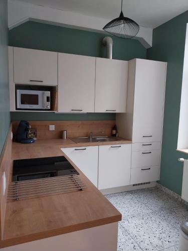 a kitchen with white cabinets and a microwave at Au Coeur de LilleMoulins in Lille