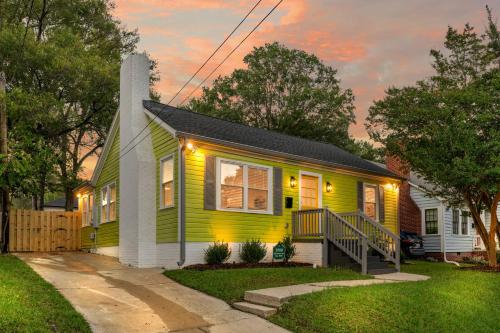 a yellow house with a porch with lights on it at Stylish 4BR Haven: Serene Backyard and Fire Pit in Charlotte