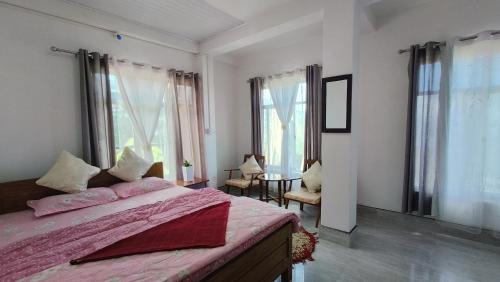 a bedroom with a bed with pink sheets and windows at Goo Sheela Homestay in Darjeeling