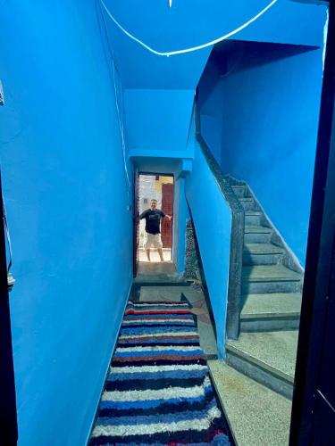 a man walking down a blue stairs with a blue wall at Blue Star Hostel in Fès