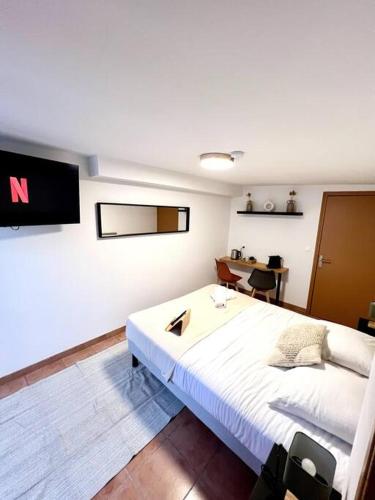 une chambre avec un grand lit blanc et un bureau dans l'établissement Les chambres de la bastide - 203, à Carcassonne