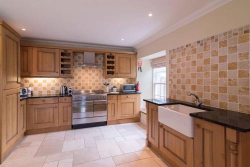 a large kitchen with wooden cabinets and a sink at The Furze Farmhouse near St Andrews in Newburgh