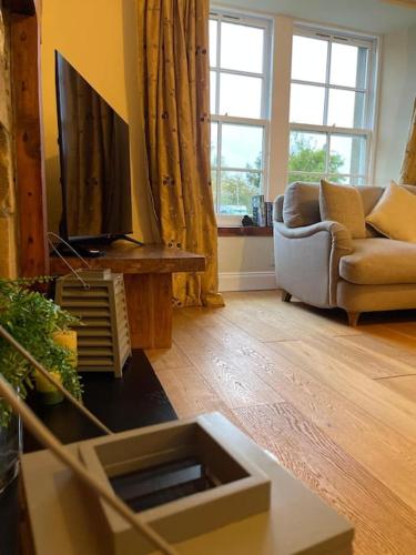 a living room with a couch and a flat screen tv at The Furze Farmhouse near St Andrews in Newburgh