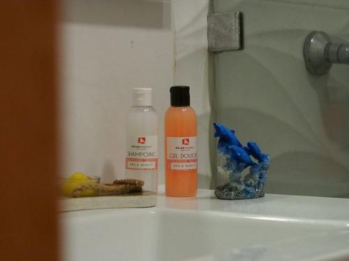a bottle of orange liquid sitting on a bathroom sink at Appart en bord de mer avec piscine vue imprenable in Aourir