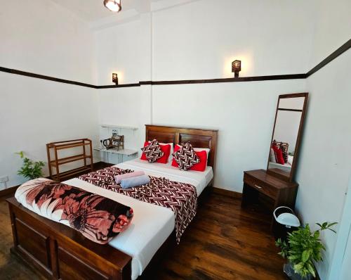 a bedroom with two beds with red pillows at Chez Allen in Nuwara Eliya
