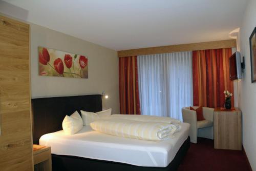 ein Hotelzimmer mit einem weißen Bett und einem Stuhl in der Unterkunft Appartements Zerzer in Ried im Oberinntal