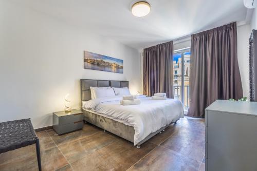 Un dormitorio con una cama grande y una ventana grande. en Spinola Seafront Deluxe, en San Julián