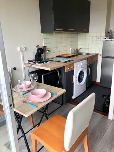 une cuisine avec une table et une machine à laver dans l'établissement Appartement luxueux avec balcon à La Défense, à La Garenne-Colombes