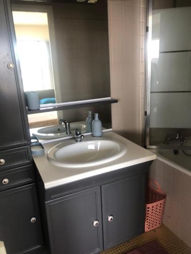 une salle de bain avec un lavabo, un miroir et une baignoire dans l'établissement Appartement luxueux avec balcon à La Défense, à La Garenne-Colombes
