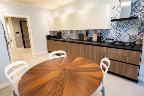 a kitchen with a wooden table and white chairs at Dreamland Golf Hotel Baku in Baku
