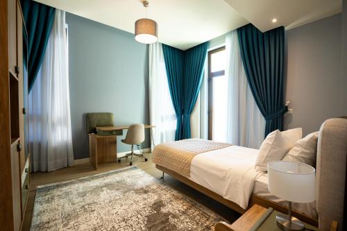 a bedroom with a bed with blue curtains and a desk at Dreamland Golf Hotel Baku in Baku