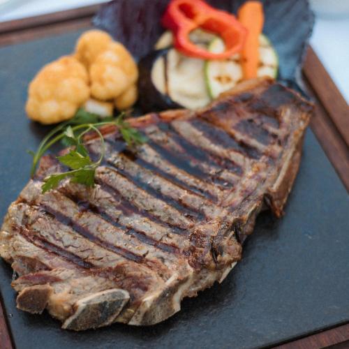 a piece of meat and vegetables on a plate at Amazona Hotel in Pristina