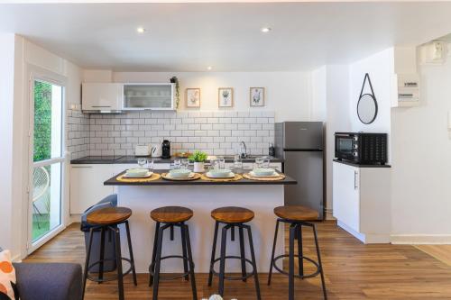 une cuisine avec trois tabourets de bar et un comptoir dans l'établissement Grand Appartement avec Balcon Hyper - Centre Tarbes, à Tarbes