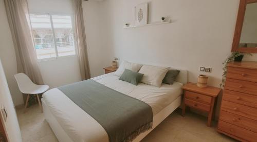a bedroom with a bed with a chair and a window at Casa de Luz - Beach & Boulevard in Torrevieja