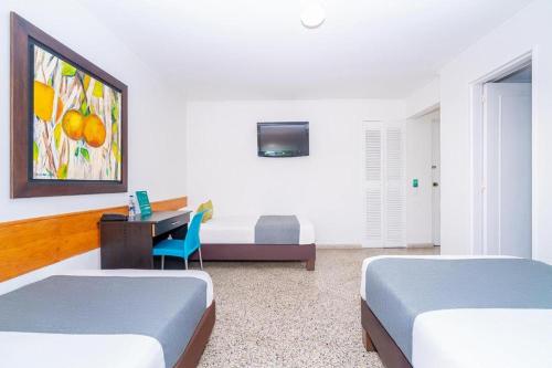 a room with two beds and a desk with a computer at HOTEL OASIS in Rionegro