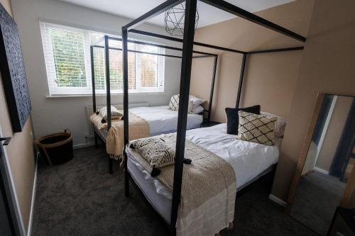 a bedroom with two four poster beds and a window at Uber Stylish 3 bedroom home off Road parking near town centre and Bike Park Wales in Merthyr Tydfil