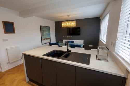 a kitchen with a sink and a living room at Uber Stylish 3 bedroom home off Road parking near town centre and Bike Park Wales in Merthyr Tydfil