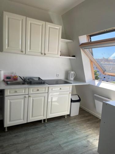 加来Grand studio Centre-ville avec ascenseur的白色的厨房配有白色橱柜和窗户