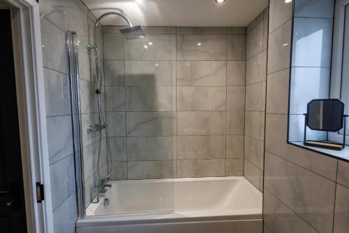 a bathroom with a tub and a glass shower at Uber Stylish 3 bedroom home off Road parking near town centre and Bike Park Wales in Merthyr Tydfil