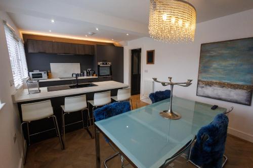 a kitchen with a glass table and some chairs at Uber Stylish 3 bedroom home off Road parking near town centre and Bike Park Wales in Merthyr Tydfil